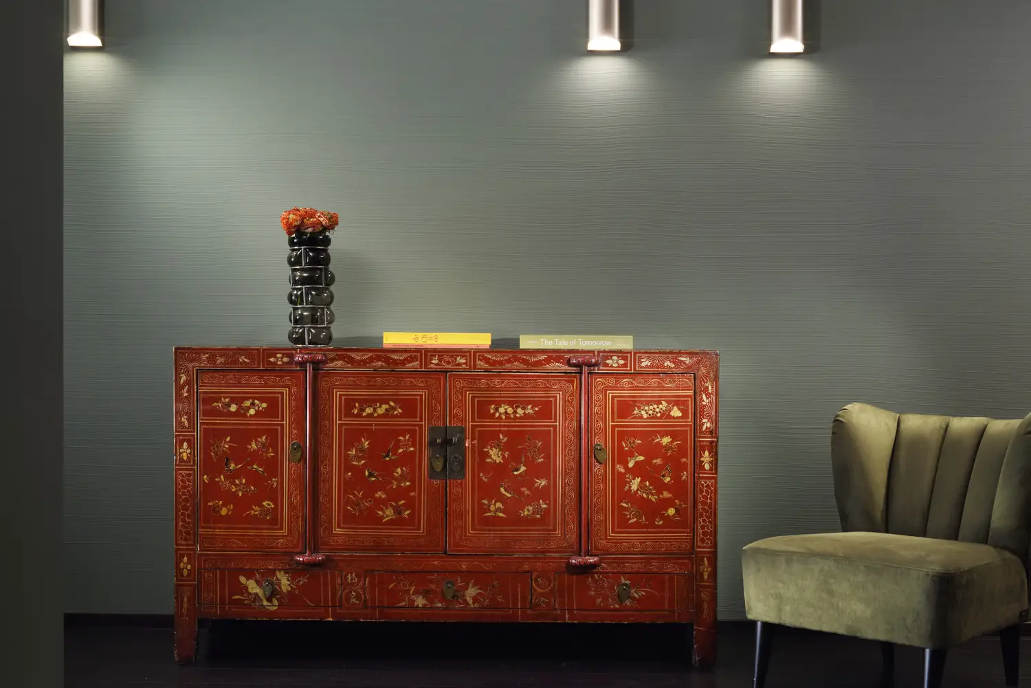 Credenza orientale laccata rossa in un ingresso, con poltroncina in velluto verde