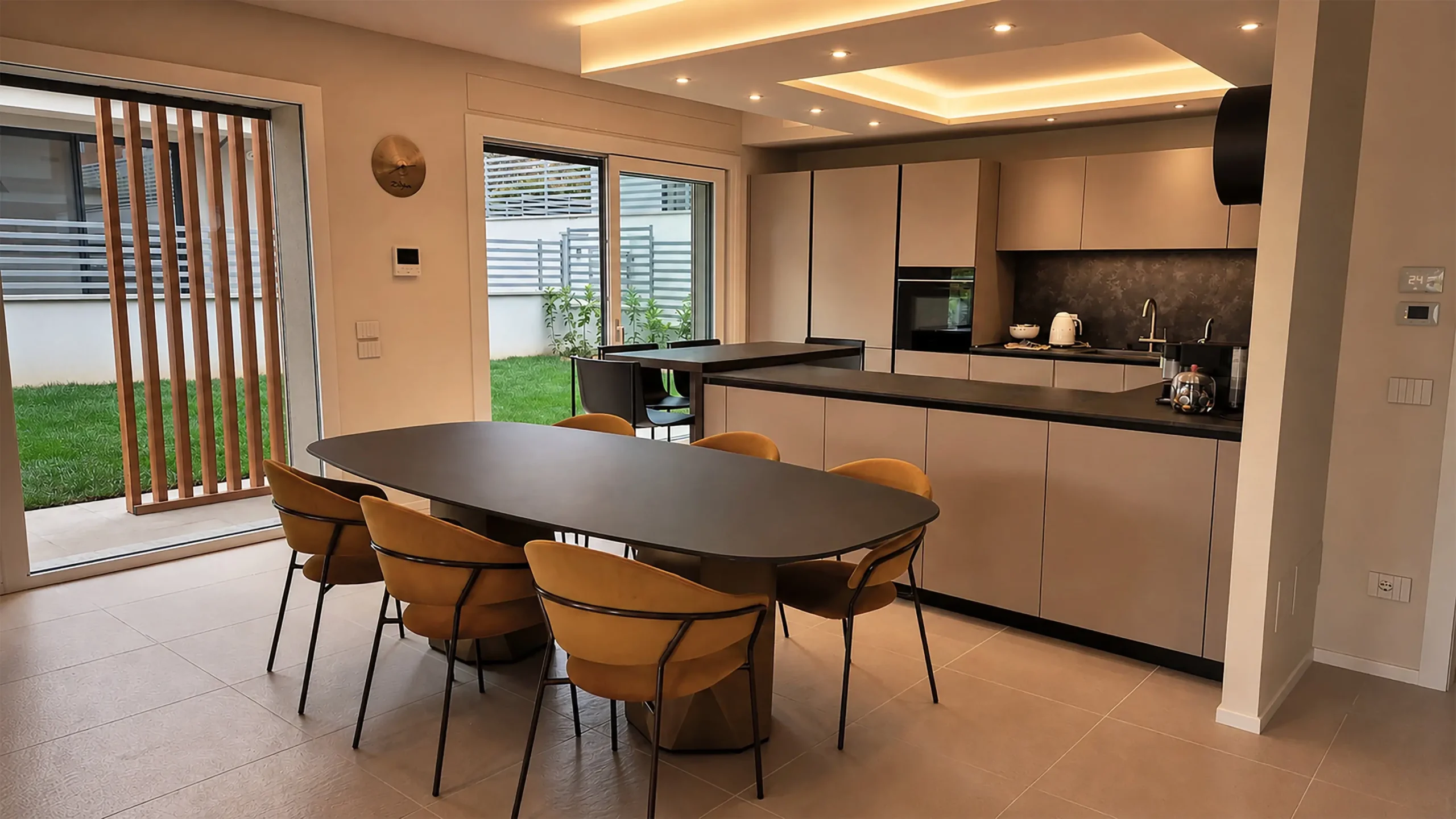 Cucina aperta sulla zona pranzo con tavolo ovale e affaccio sul giardino