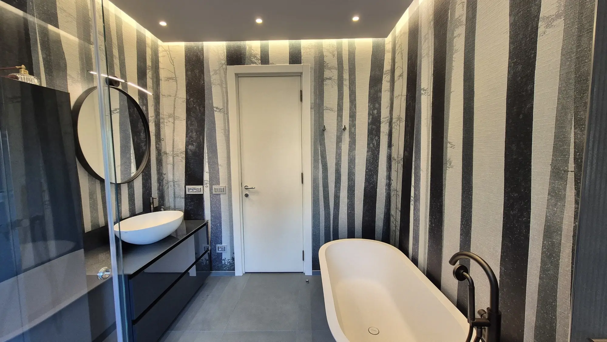 Bagno padronale con vasca freestanding e rivestimento a bande marmoree