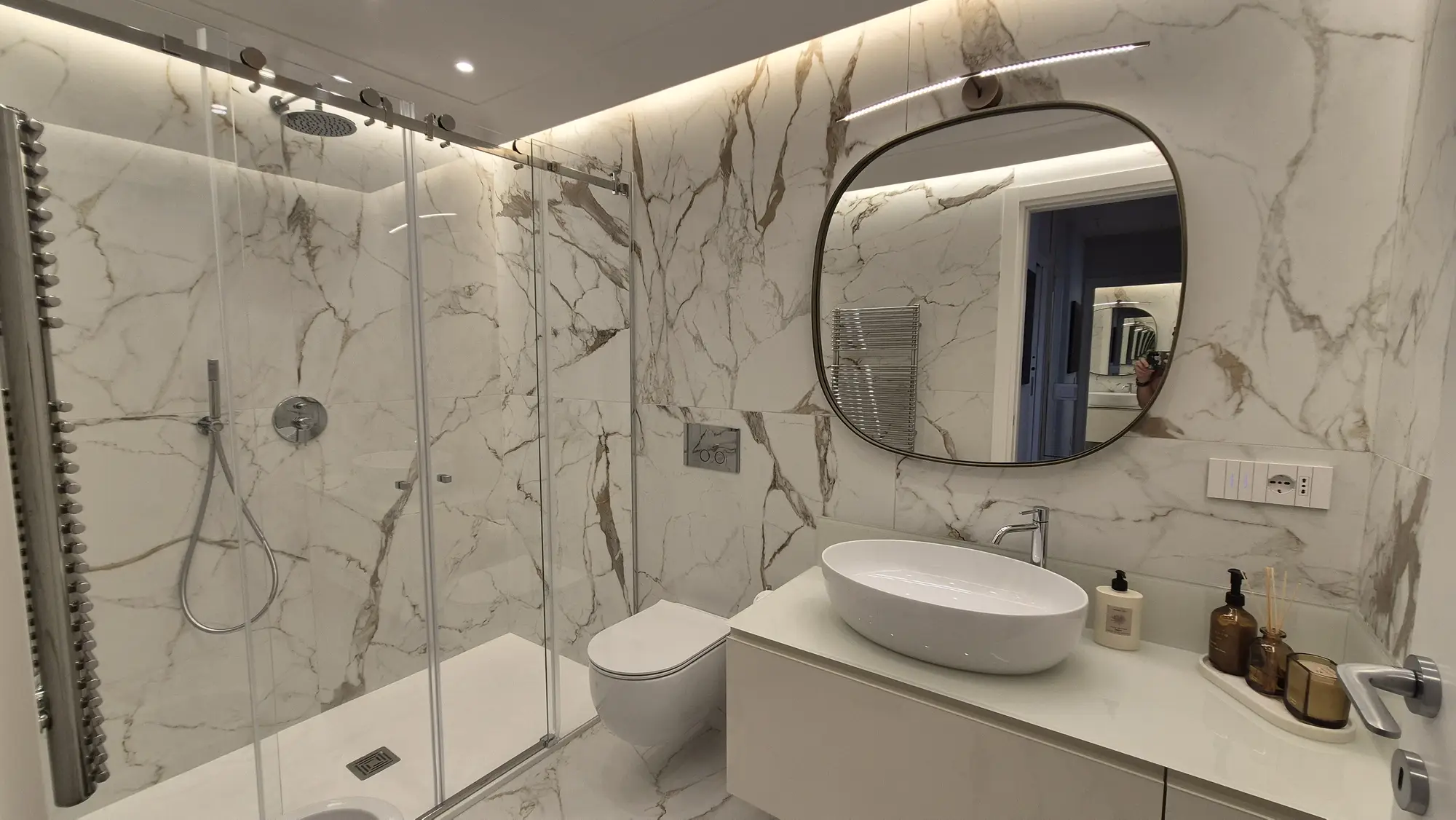Bagno rivestito in gres effetto marmo bianco con luce a led perimetrale