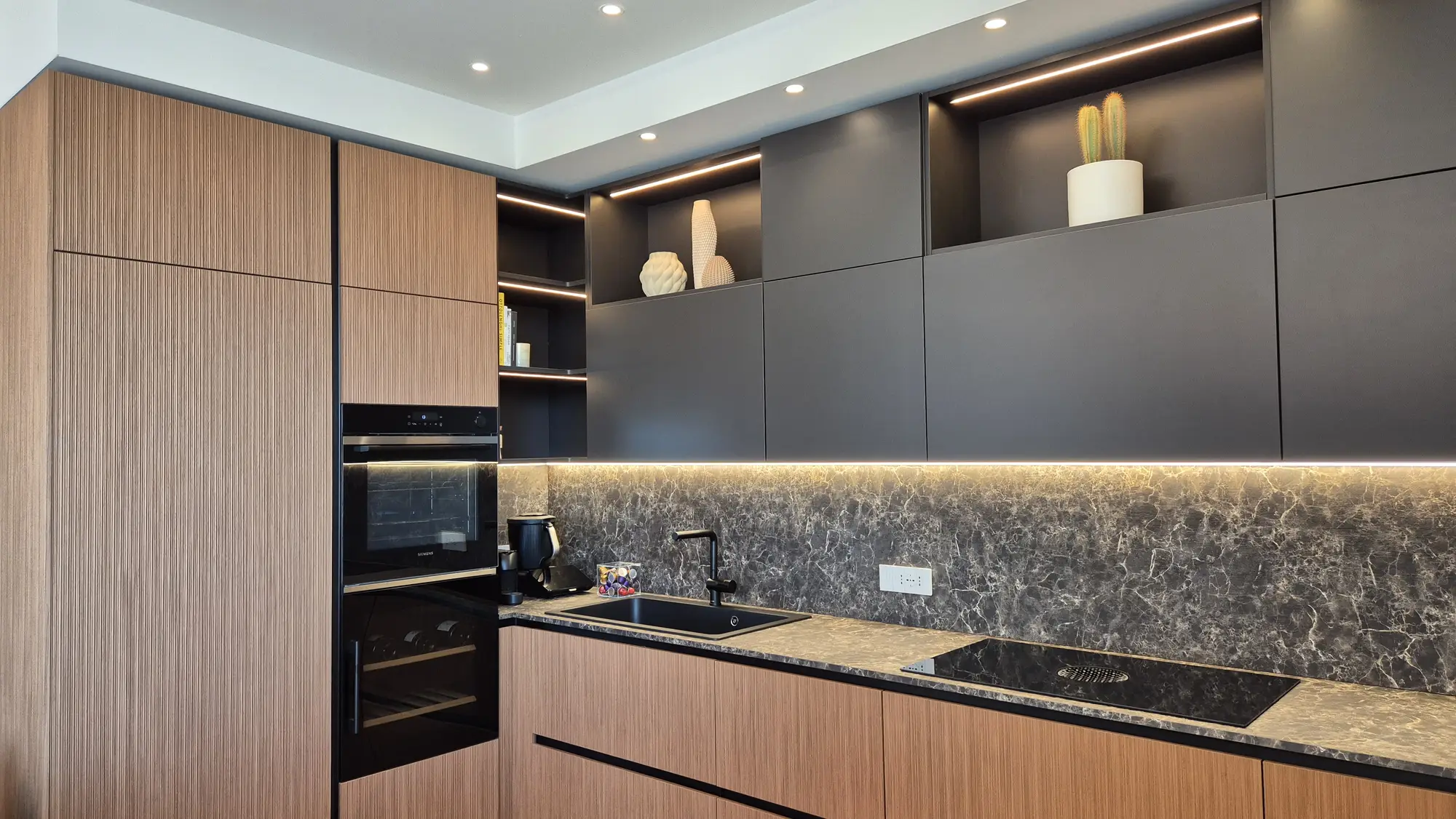 Angolo cottura con colonne in rovere, pensili laccati antracite e schienale effetto marmo