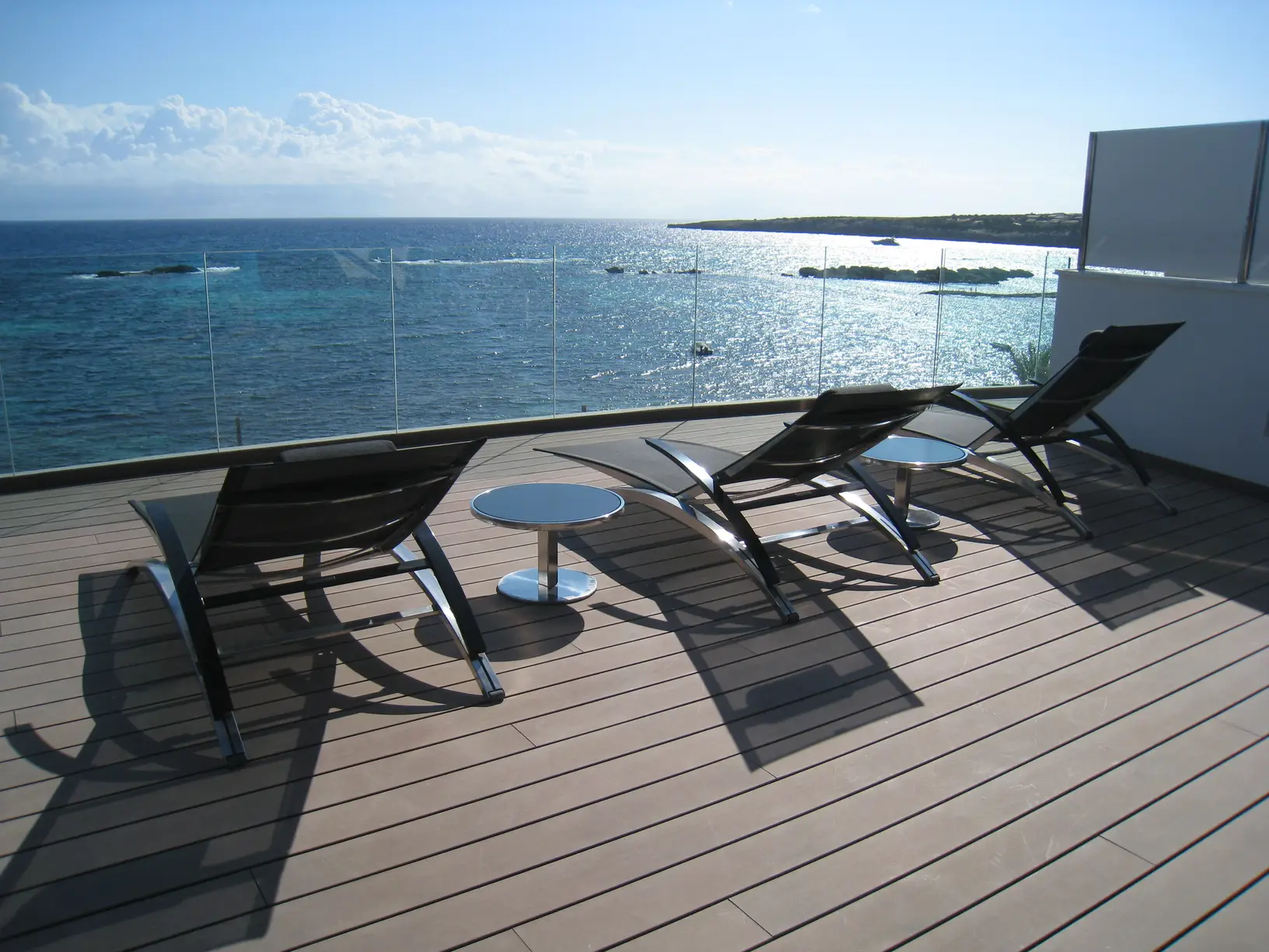 Solarium su terrazza affacciata sul mare, con lettini e parapetto in vetro
