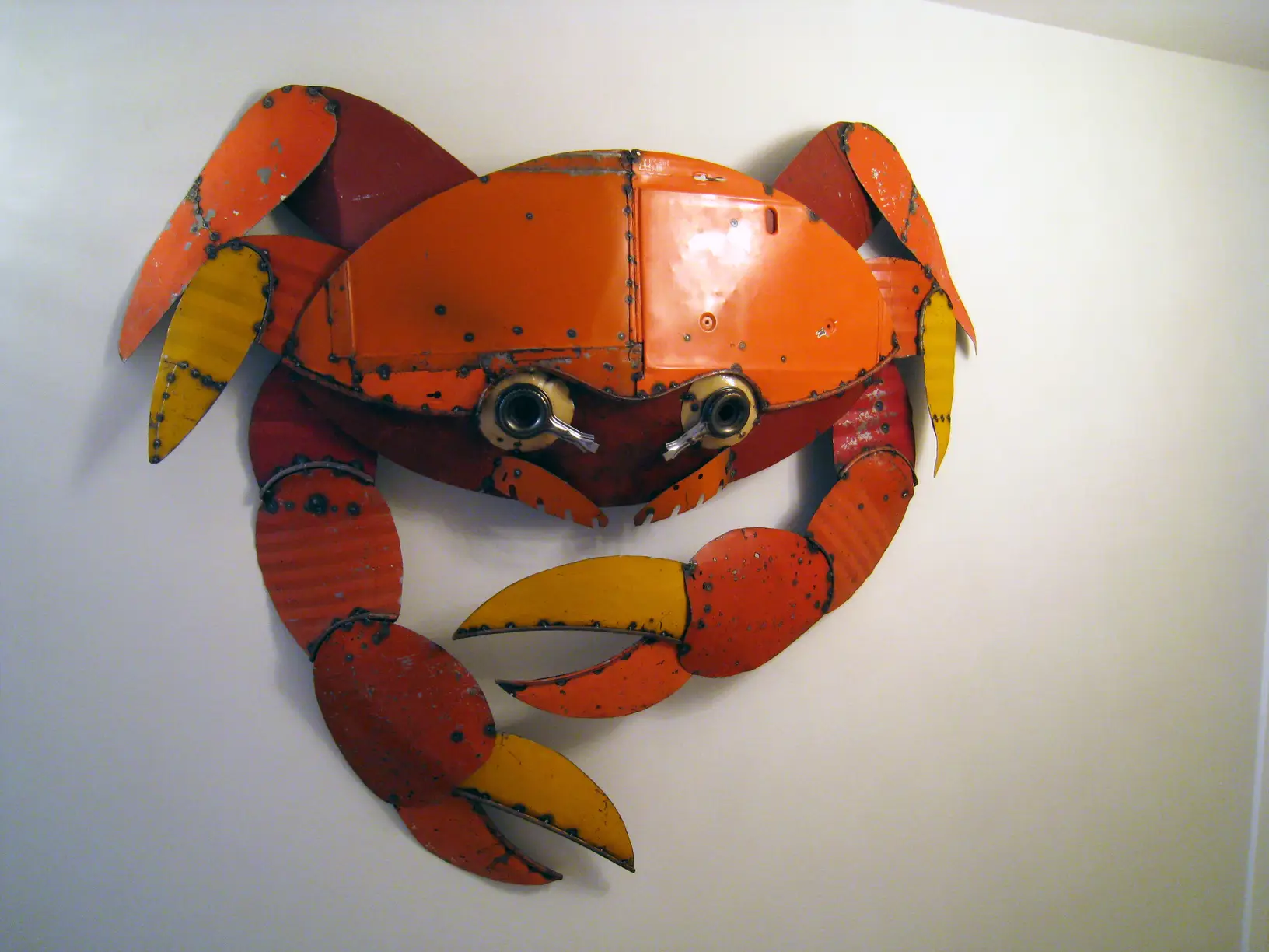 Scultura in metallo a forma di granchio, appesa a una parete bianca