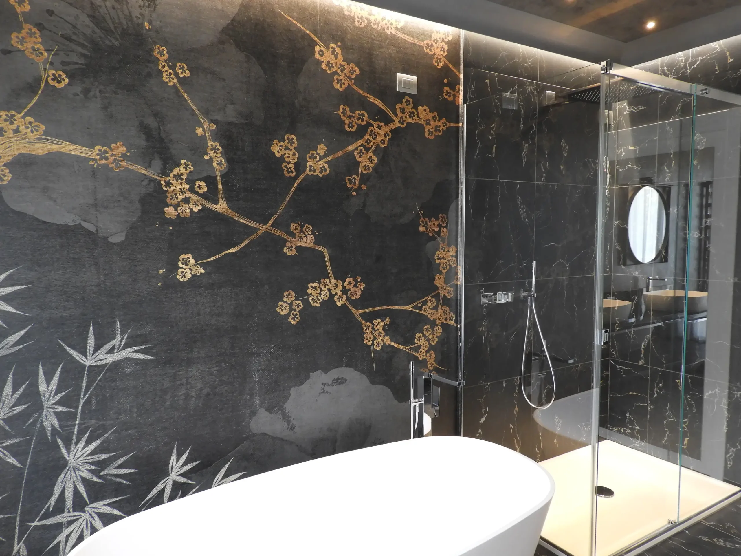 Vasca freestanding davanti a una parete decorativa con rami dorati