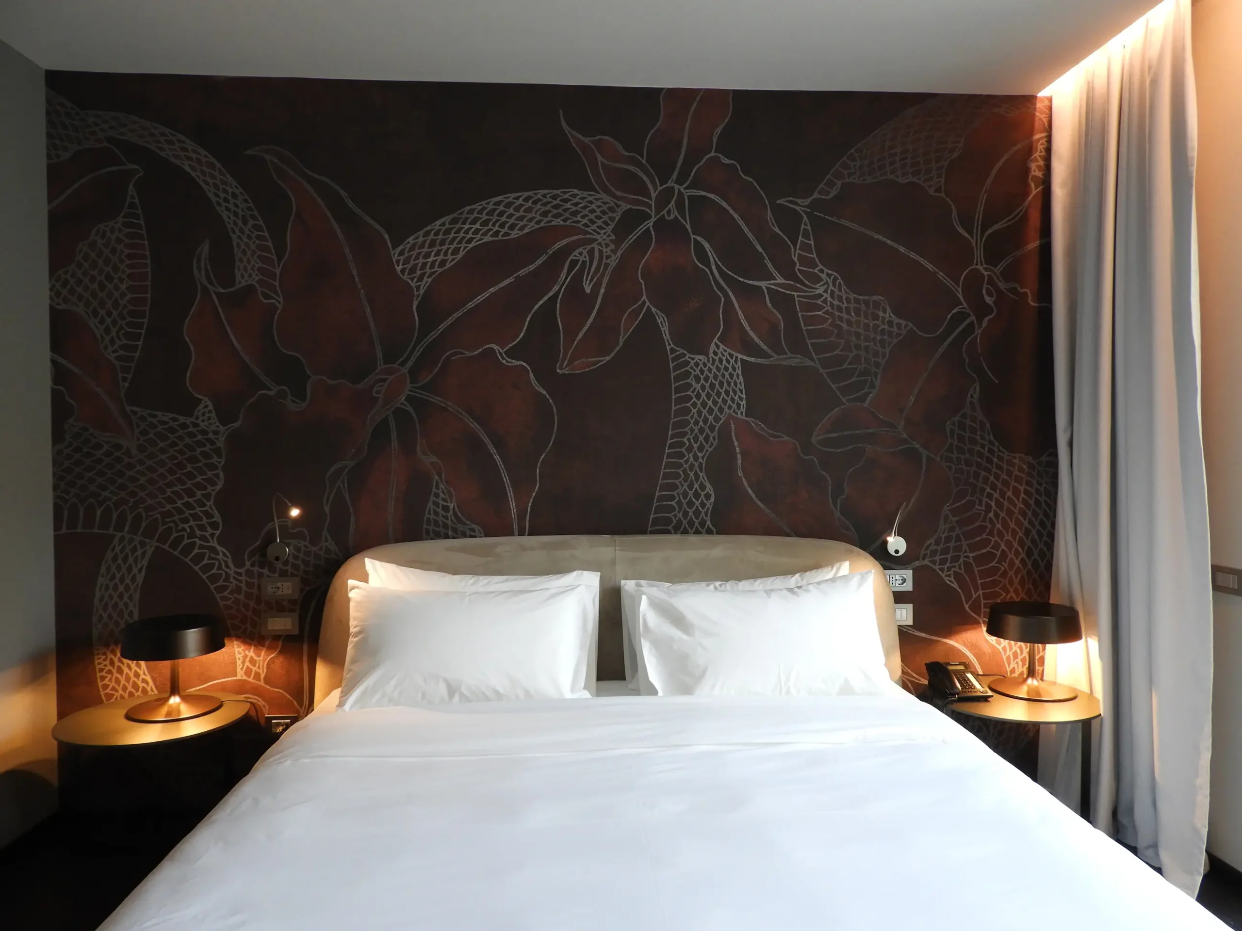 Camera da letto con parete bordeaux disegnata, vista frontale del letto
