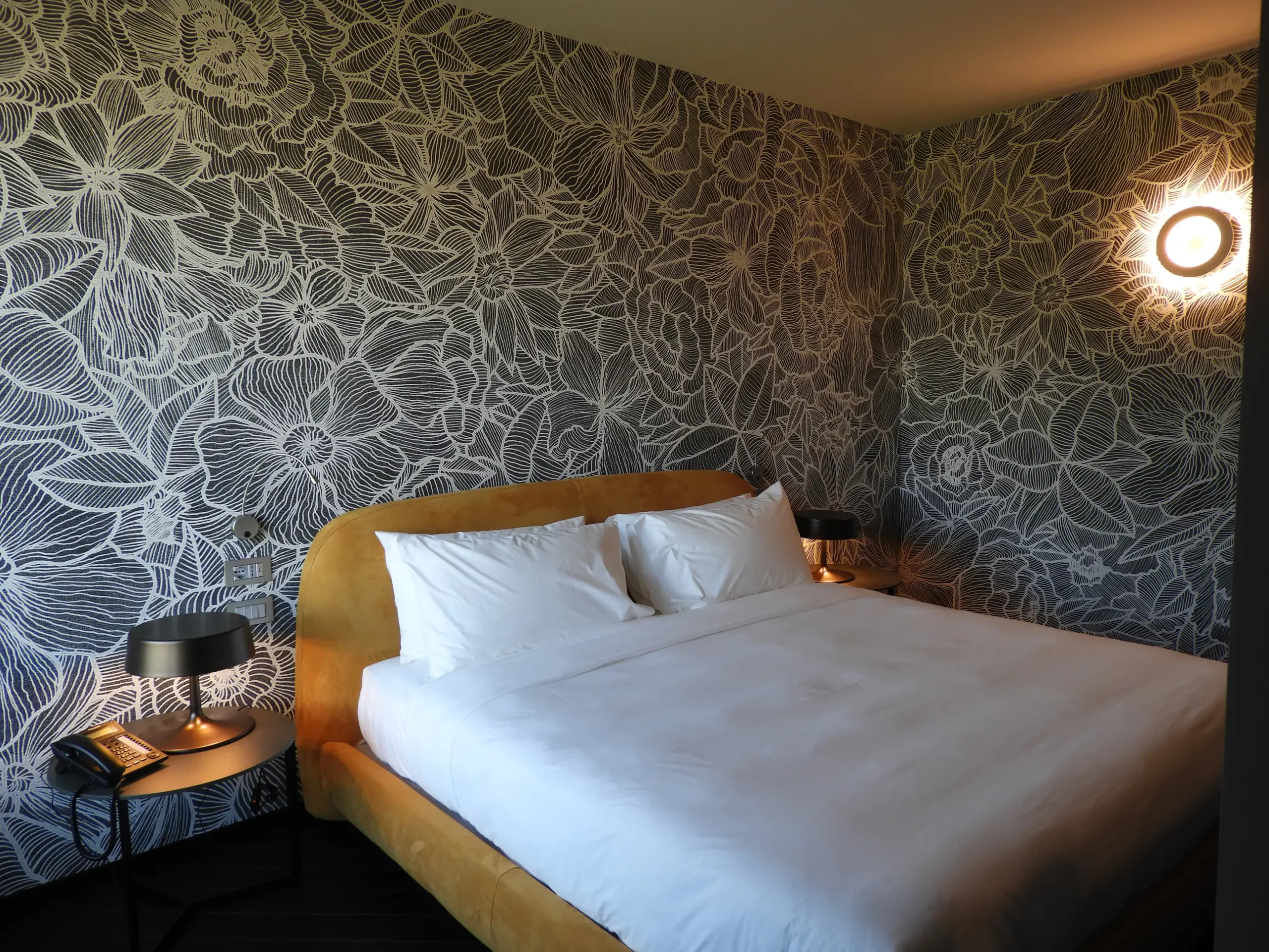 Camera da letto con carta da parati floreale e letto rivestito in velluto ocra